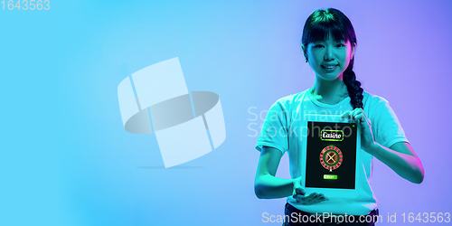 Image of Online gambling, casino concept. Young asian woman holding devices with lottery, casino cover in neon light