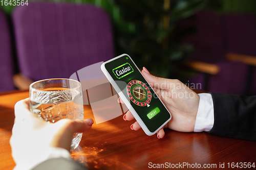 Image of Online gambling, casino concept. Hand holding device with lottery, casino cover