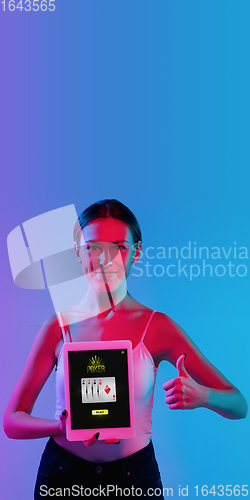 Image of Online gambling, casino concept. Young woman holding devices with lottery, casino cover in neon light