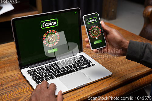 Image of Online gambling, casino concept. Hand near laptop, device with lottery, casino cover