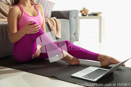 Image of Beautiful young woman working out indoors, doing yoga exercise on gray mat at home