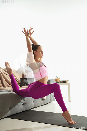 Image of Beautiful young woman working out indoors, doing yoga exercise on gray mat at home
