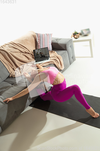 Image of Beautiful young woman working out indoors, doing yoga exercise on gray mat at home