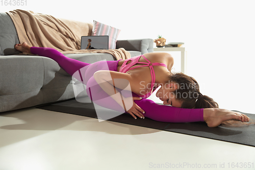 Image of Beautiful young woman working out indoors, doing yoga exercise on gray mat at home