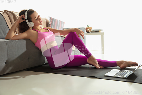 Image of Beautiful young woman working out indoors, doing yoga exercise on gray mat at home