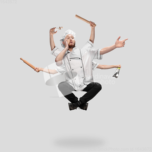 Image of Cooker, chef, baker in uniform multitask like shiva isolated on gray studio background