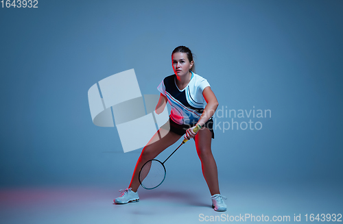 Image of Beautiful handicap woman practicing in badminton isolated on blue background in neon light