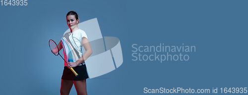 Image of Beautiful handicap woman practicing in badminton isolated on blue background in neon light