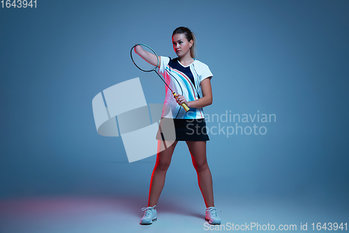 Image of Beautiful handicap woman practicing in badminton isolated on blue background in neon light