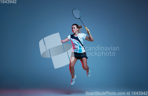 Image of Beautiful handicap woman practicing in badminton isolated on blue background in neon light