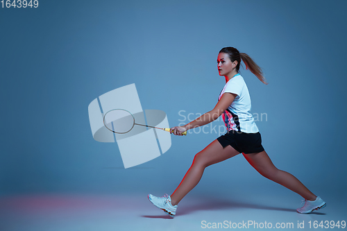 Image of Beautiful handicap woman practicing in badminton isolated on blue background in neon light