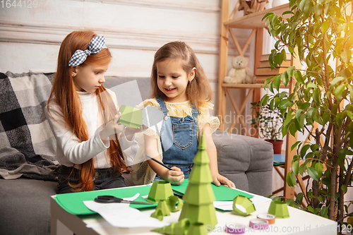 Image of Two little children, girls together in creativity of the house. Happy kids make handmade toys for games or New Year celebration