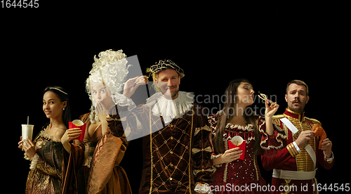 Image of Medieval people as a royalty persons in vintage clothing on dark background. Concept of comparison of eras, modernity and renaissance. Creative collage.