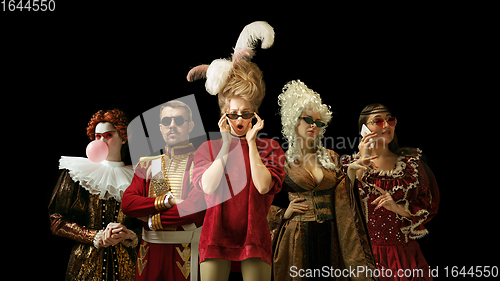 Image of Medieval people as a royalty persons in vintage clothing on dark background. Concept of comparison of eras, modernity and renaissance. Creative collage.