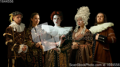 Image of Medieval people as a royalty persons in vintage clothing on dark background. Concept of comparison of eras, modernity and renaissance. Creative collage.