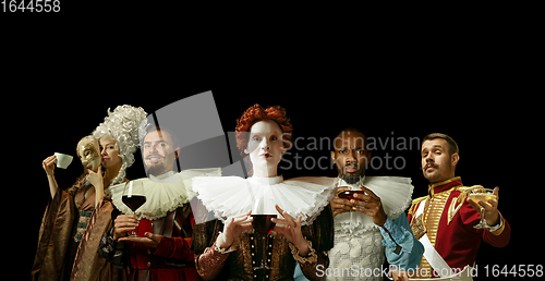 Image of Medieval people as a royalty persons in vintage clothing on dark background. Concept of comparison of eras, modernity and renaissance. Creative collage.