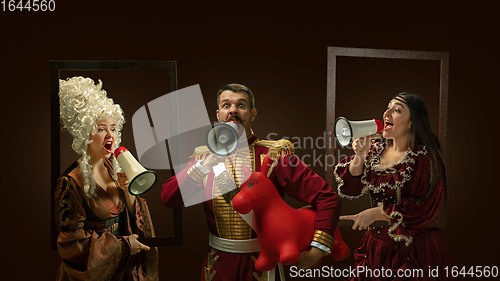 Image of Medieval people as a royalty persons in vintage clothing on dark background. Concept of comparison of eras, modernity and renaissance. Creative collage.