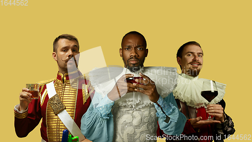 Image of Medieval men as a royalty persons in vintage clothing on yellow background. Concept of comparison of eras, modernity and renaissance. Creative collage.