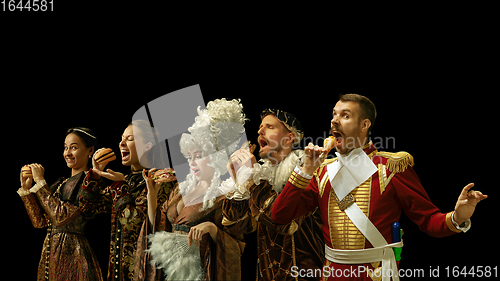 Image of Medieval people as a royalty persons in vintage clothing on dark background. Concept of comparison of eras, modernity and renaissance. Creative collage.