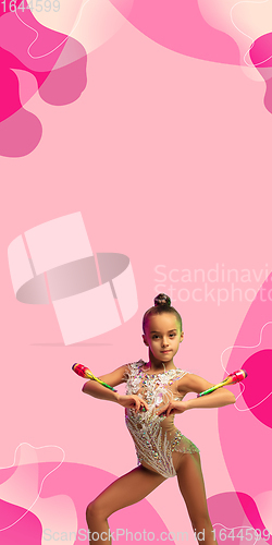 Image of Little caucasian girl, rhytmic gymnast training, performing on pink studio background with geometric design. Vertical flyer