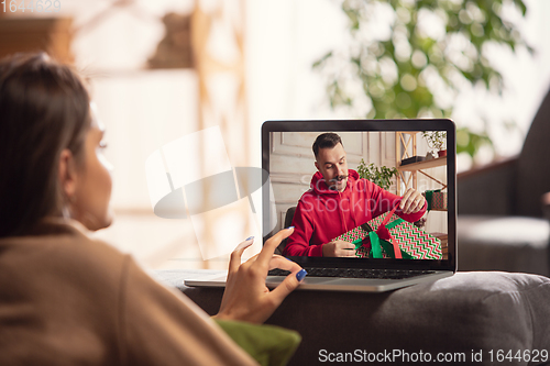 Image of Celebration and holidays during quarantine concept. Friends or family unpacking gifts while talking using video call