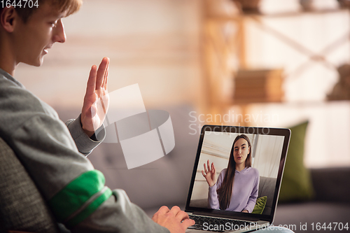 Image of Celebration and holidays during quarantine concept. Friends or family unpacking gifts while talking using video call