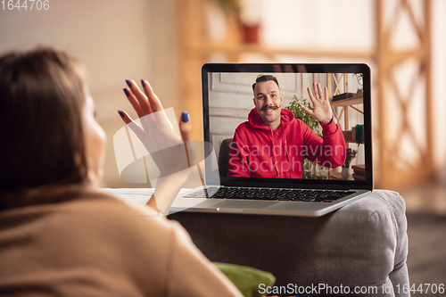 Image of Celebration and holidays during quarantine concept. Friends or family unpacking gifts while talking using video call
