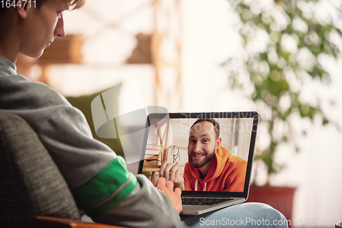 Image of Celebration and holidays during quarantine concept. Friends or family unpacking gifts while talking using video call