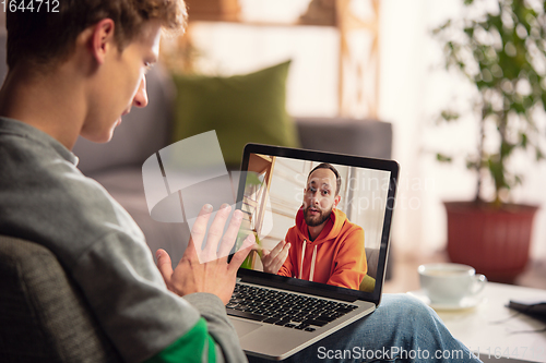 Image of Celebration and holidays during quarantine concept. Friends or family unpacking gifts while talking using video call