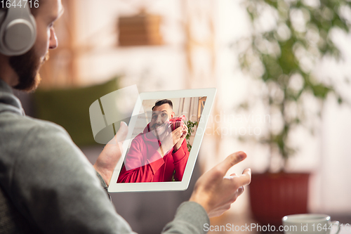 Image of Celebration and holidays during quarantine concept. Friends or family unpacking gifts while talking using video call