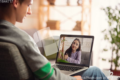 Image of Celebration and holidays during quarantine concept. Friends or family unpacking gifts while talking using video call