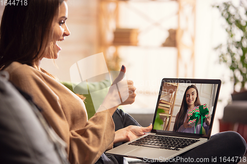 Image of Celebration and holidays during quarantine concept. Friends or family unpacking gifts while talking using video call