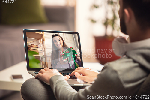 Image of Celebration and holidays during quarantine concept. Friends or family unpacking gifts while talking using video call