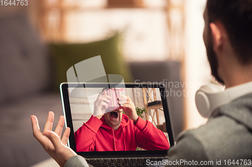 Image of Celebration and holidays during quarantine concept. Friends or family unpacking gifts while talking using video call