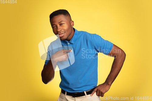 Image of Young african-american man\'s portrait isolated on yellow studio background, facial expression. Beautiful male half-lenght portrait with copyspace.