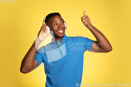 Image of Young african-american man\'s portrait isolated on yellow studio background, facial expression. Beautiful male half-lenght portrait with copyspace.