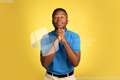 Image of Young african-american man\'s portrait isolated on yellow studio background, facial expression. Beautiful male half-lenght portrait with copyspace.