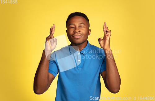 Image of Young african-american man\'s portrait isolated on yellow studio background, facial expression. Beautiful male half-lenght portrait with copyspace.