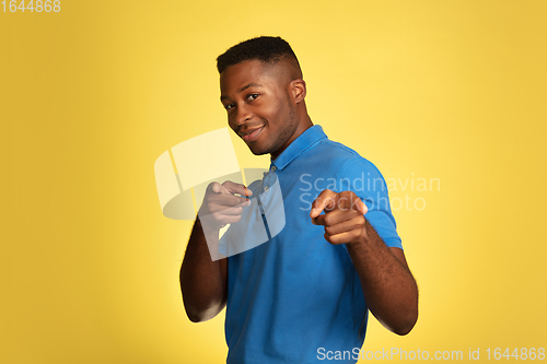 Image of Young african-american man\'s portrait isolated on yellow studio background, facial expression. Beautiful male half-lenght portrait with copyspace.