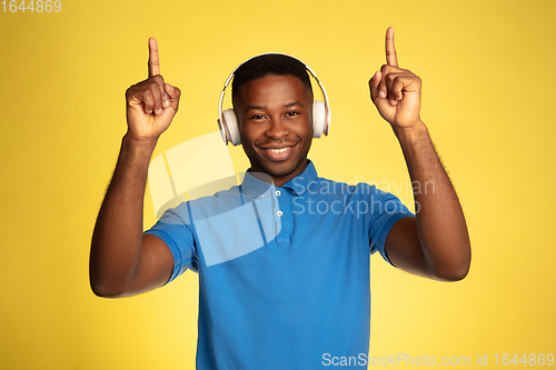 Image of Young african-american man\'s portrait isolated on yellow studio background, facial expression. Beautiful male half-lenght portrait with copyspace.