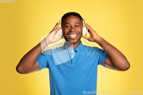 Image of Young african-american man\'s portrait isolated on yellow studio background, facial expression. Beautiful male half-lenght portrait with copyspace.