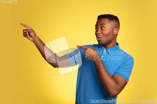 Image of Young african-american man\'s portrait isolated on yellow studio background, facial expression. Beautiful male half-lenght portrait with copyspace.