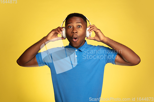 Image of Young african-american man\'s portrait isolated on yellow studio background, facial expression. Beautiful male half-lenght portrait with copyspace.