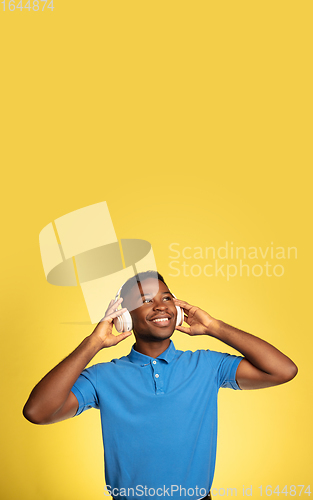 Image of Young african-american man\'s portrait isolated on yellow studio background, facial expression. Beautiful male half-lenght portrait with copyspace.