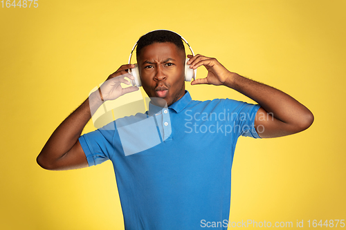 Image of Young african-american man\'s portrait isolated on yellow studio background, facial expression. Beautiful male half-lenght portrait with copyspace.