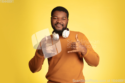 Image of Young african-american man\'s portrait isolated on yellow studio background, facial expression. Beautiful male half-lenght portrait with copyspace.