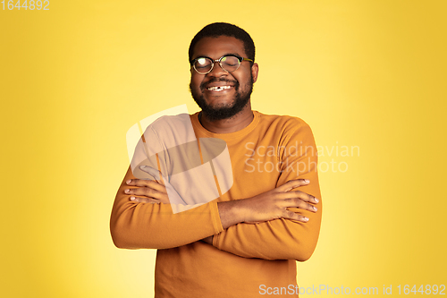 Image of Young african-american man\'s portrait isolated on yellow studio background, facial expression. Beautiful male half-lenght portrait with copyspace.