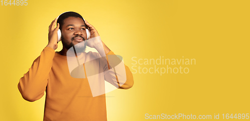 Image of Young african-american man\'s portrait isolated on yellow studio background, facial expression. Beautiful male half-lenght portrait with copyspace.