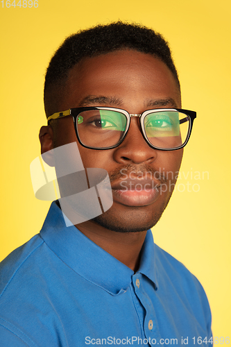 Image of Young african-american man\'s portrait isolated on yellow studio background, facial expression. Beautiful male half-lenght portrait with copyspace.