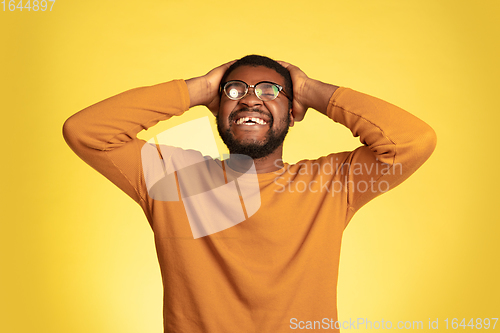 Image of Young african-american man\'s portrait isolated on yellow studio background, facial expression. Beautiful male half-lenght portrait with copyspace.